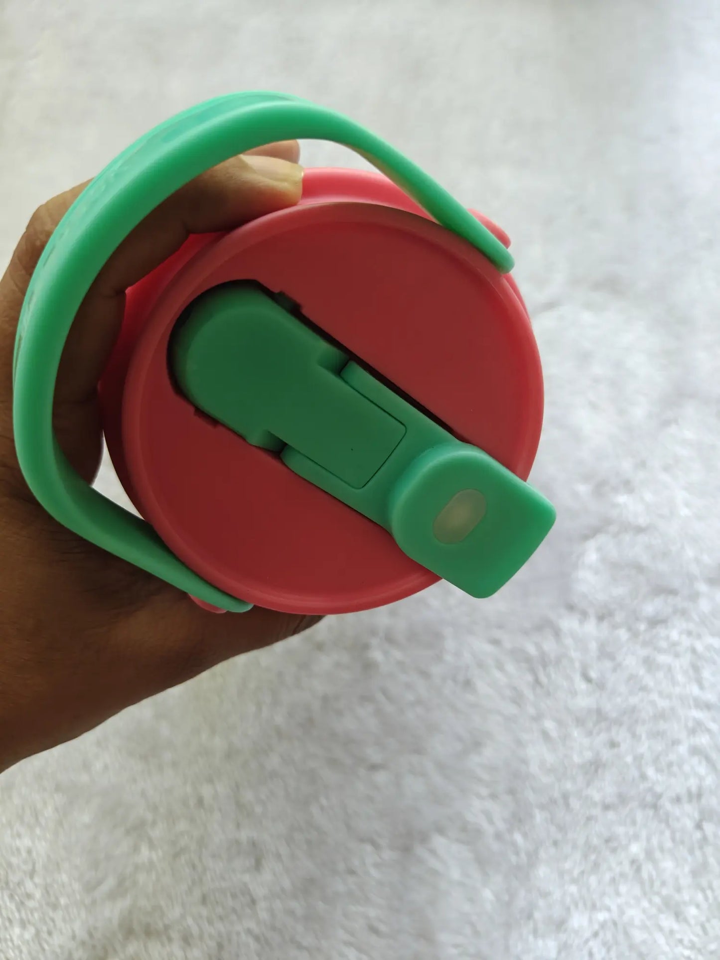 Red and green lid held by a hand on a white background