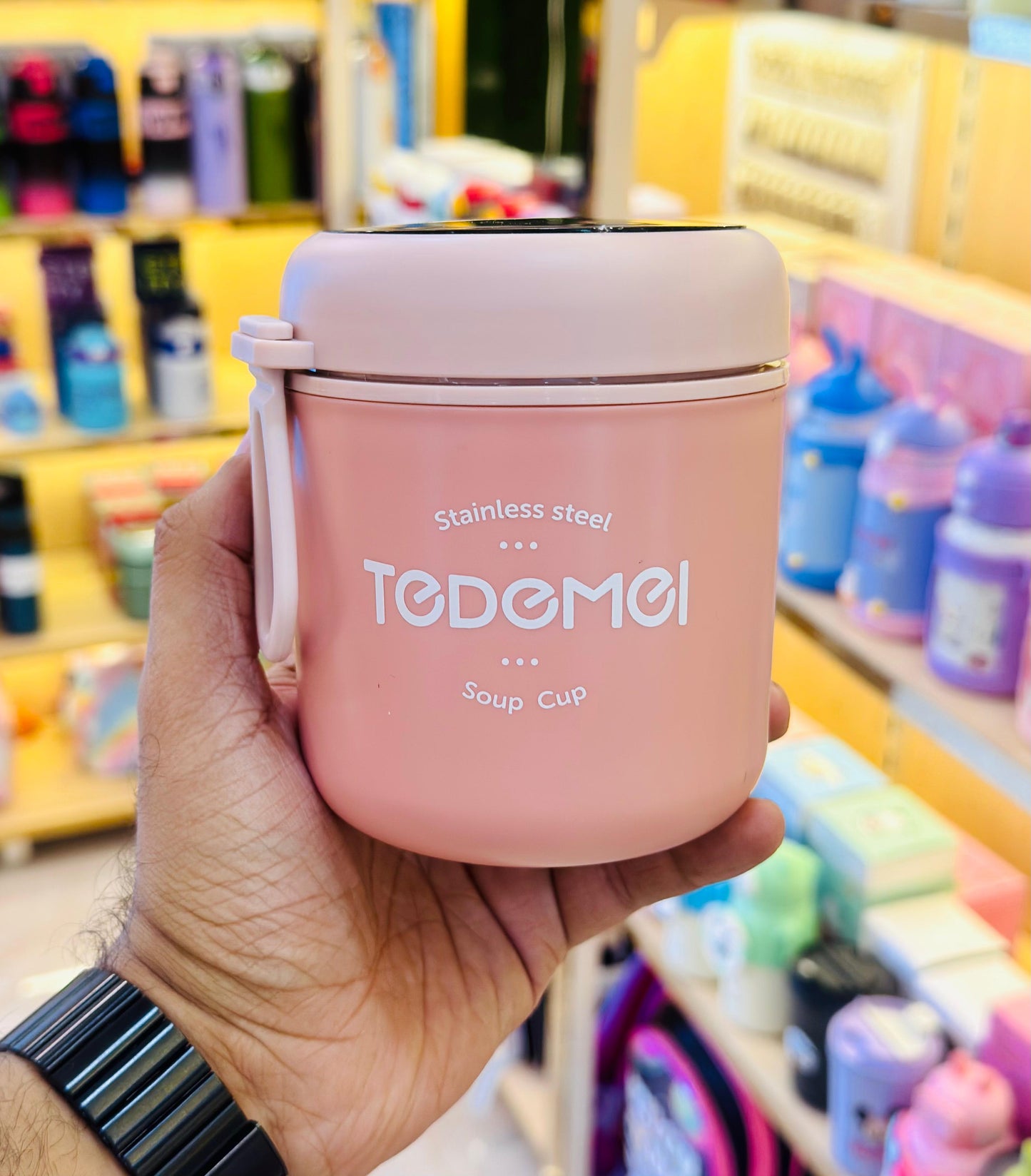 Pink soup cup with 'TODEMOI' branding held in a hand against a store background.