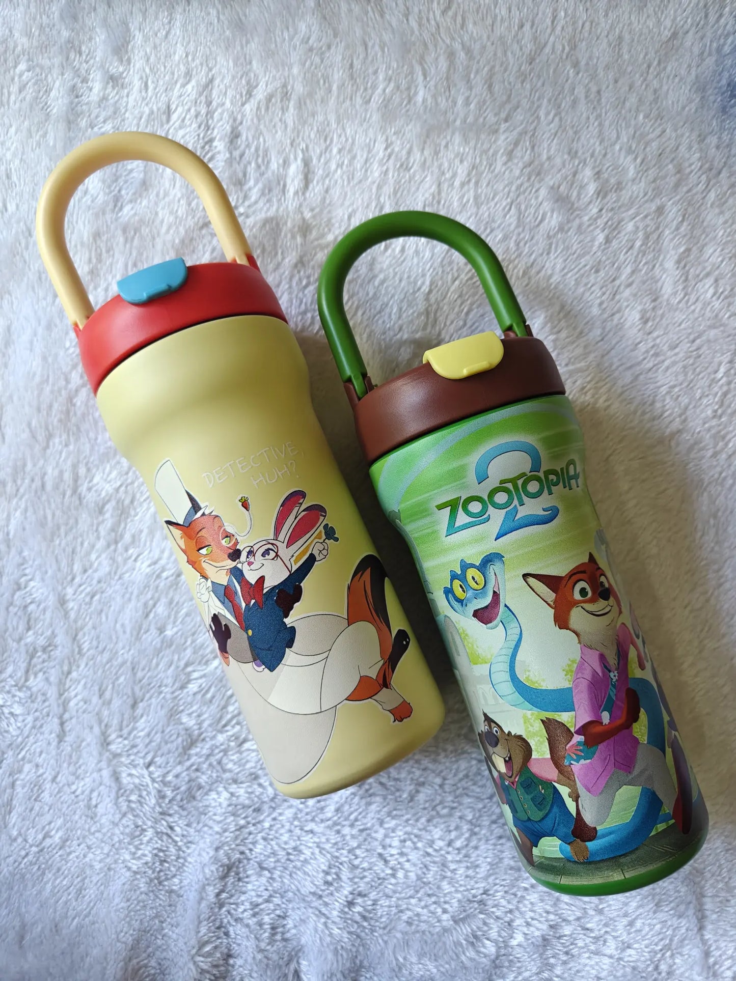 Two children's water bottles with cartoon characters on a textured white background