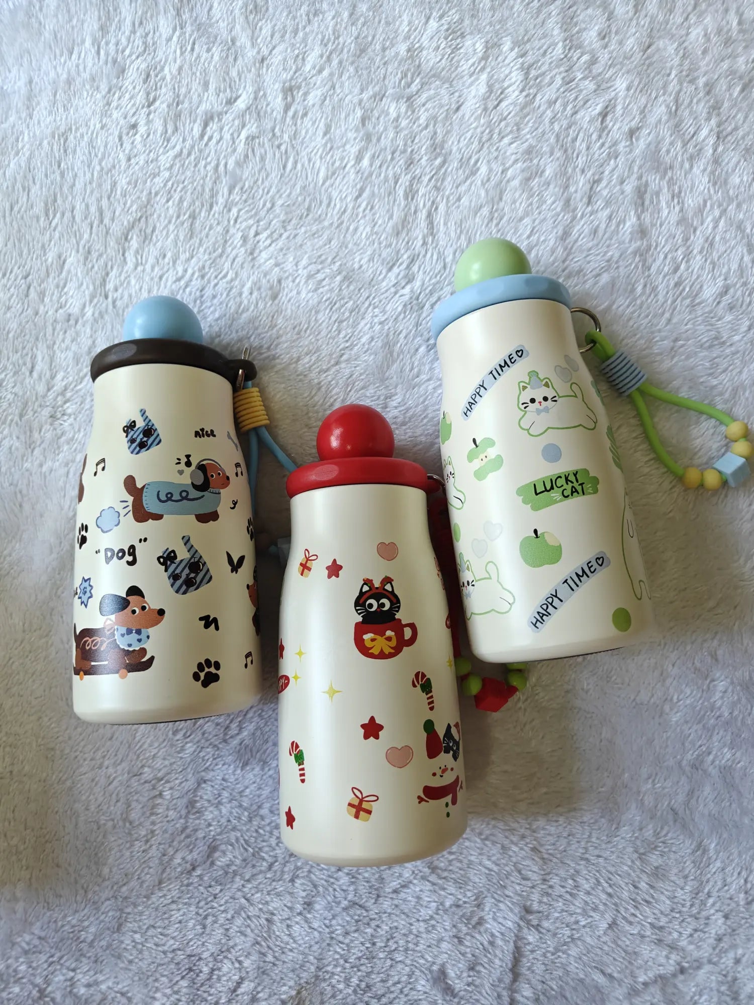 Three children's water bottles with cartoon designs on a textured white surface