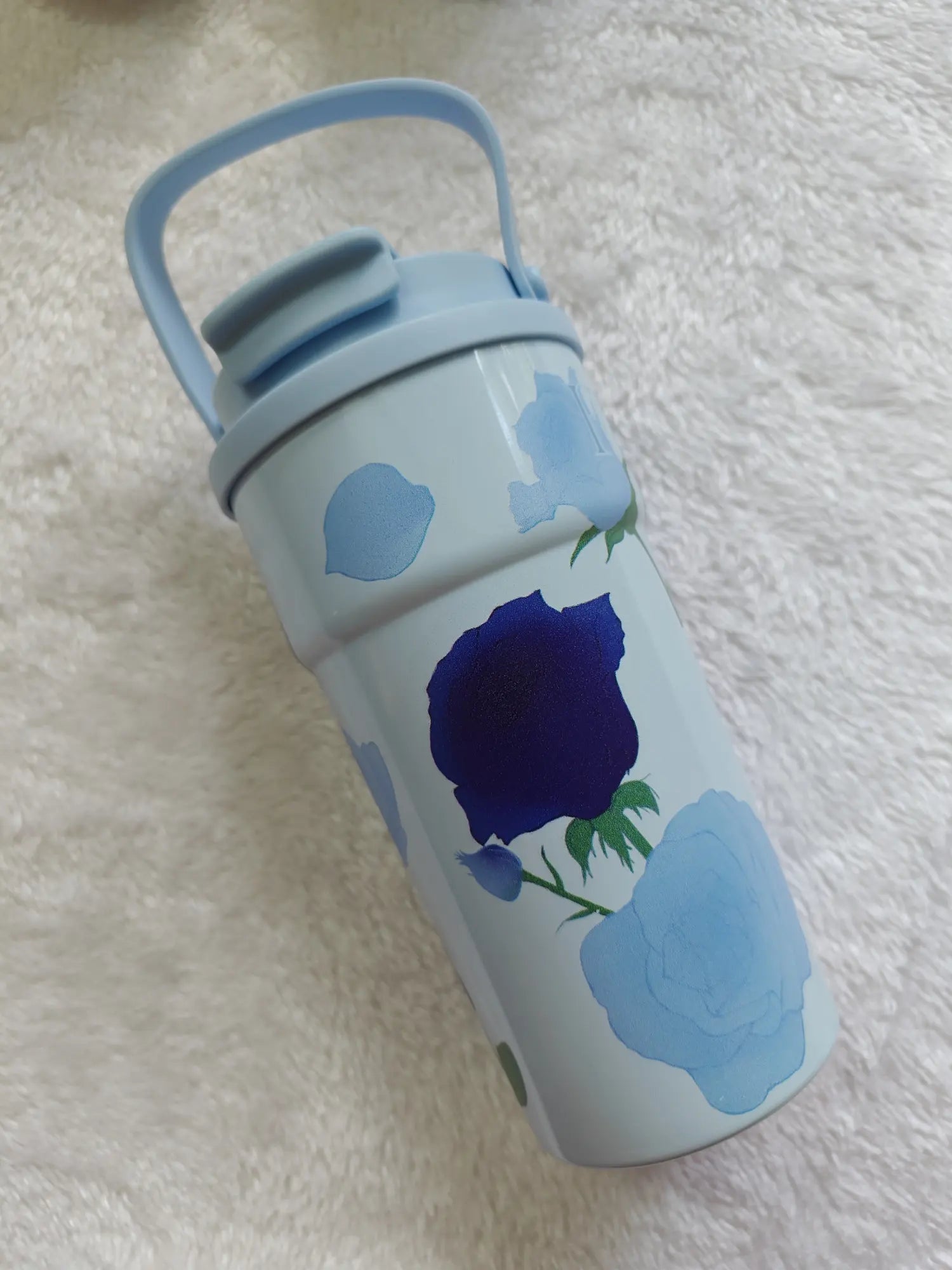 Water bottle with blue floral design on a textured white surface