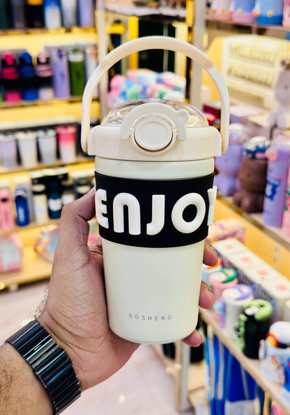 Hand holding a white tumbler with 'ENJO' branding in a store setting