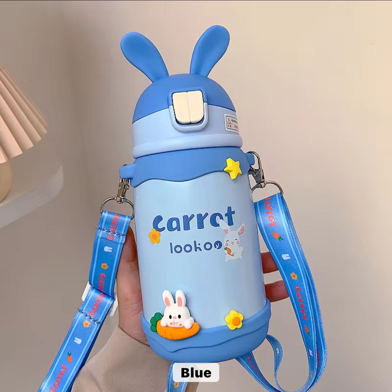 Blue water bottle with bunny design and strap on a neutral background