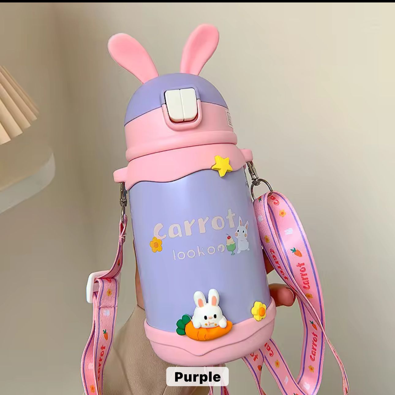 Purple water bottle with pink bunny ears and strap on a neutral background