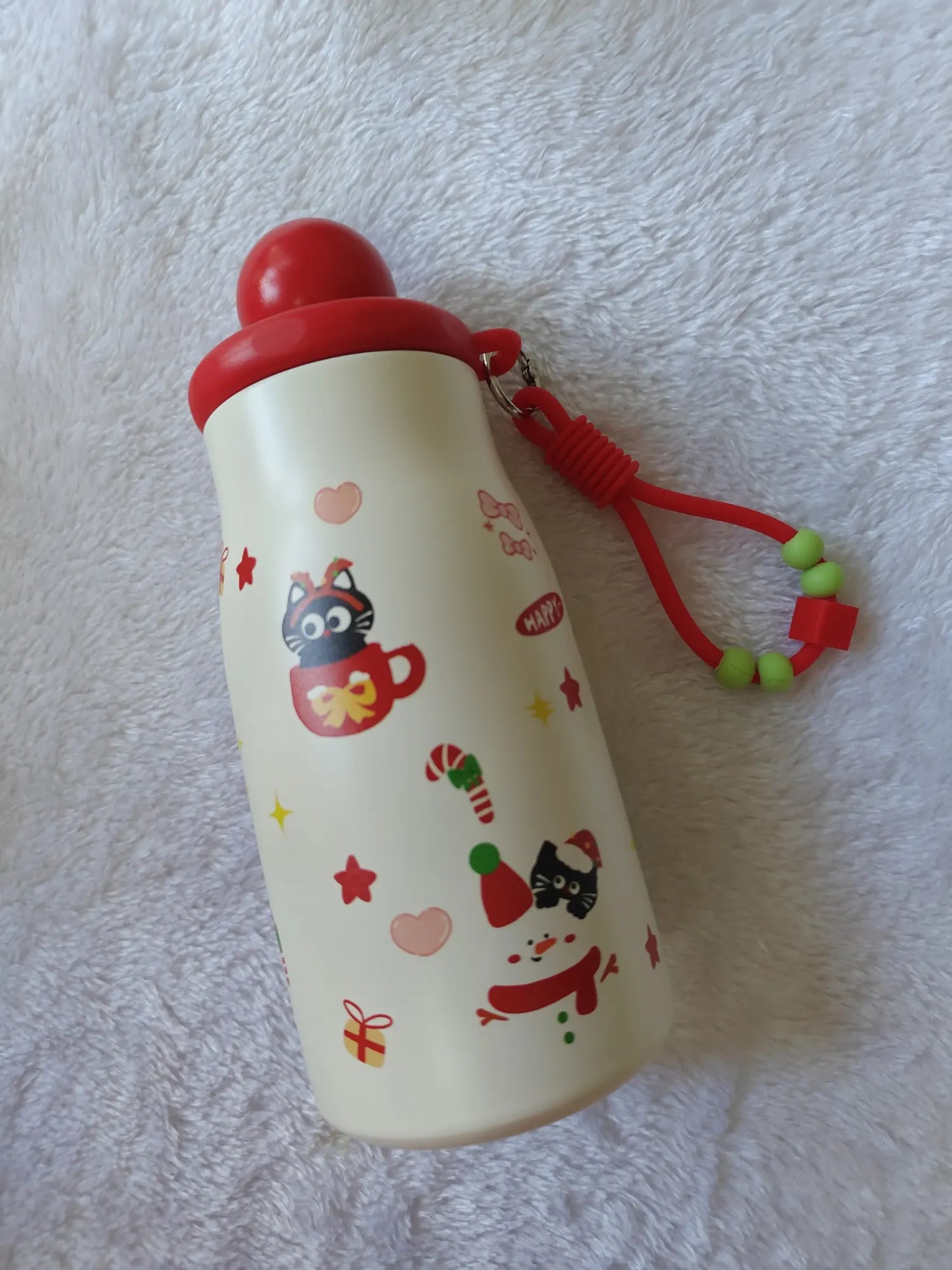 White water bottle with red lid and cat illustrations on a textured white background