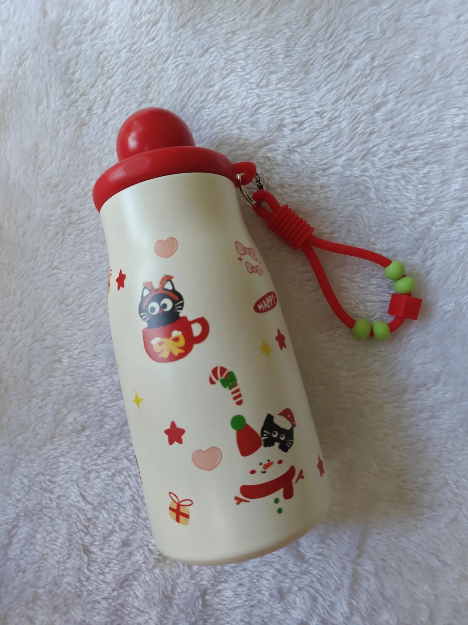 White water bottle with red lid and cat illustrations on a textured white background