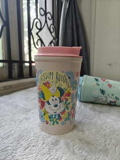 Tumbler with floral design and pink lid on a textured surface