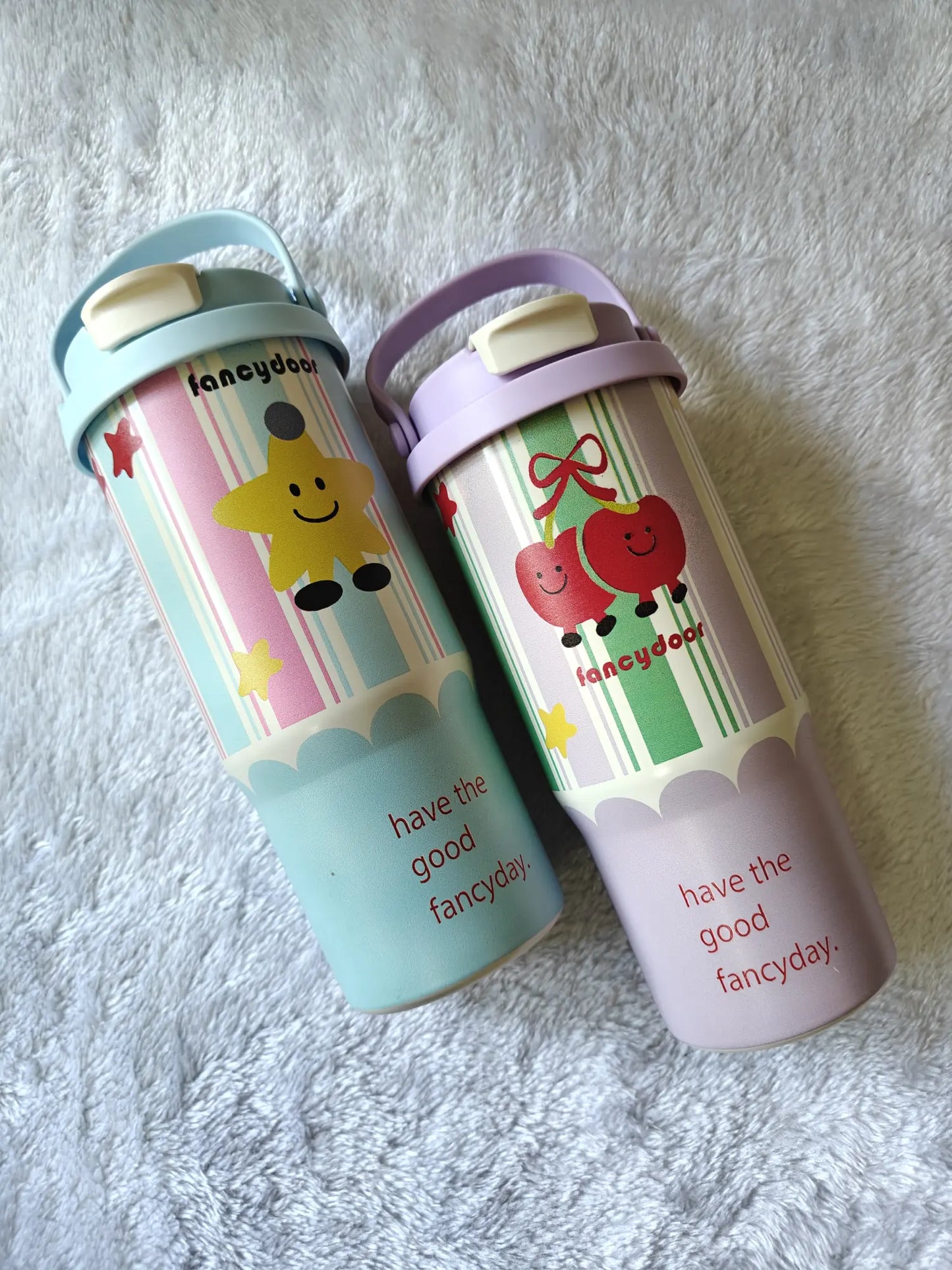 Two colorful water bottles with cartoon designs on a textured surface
