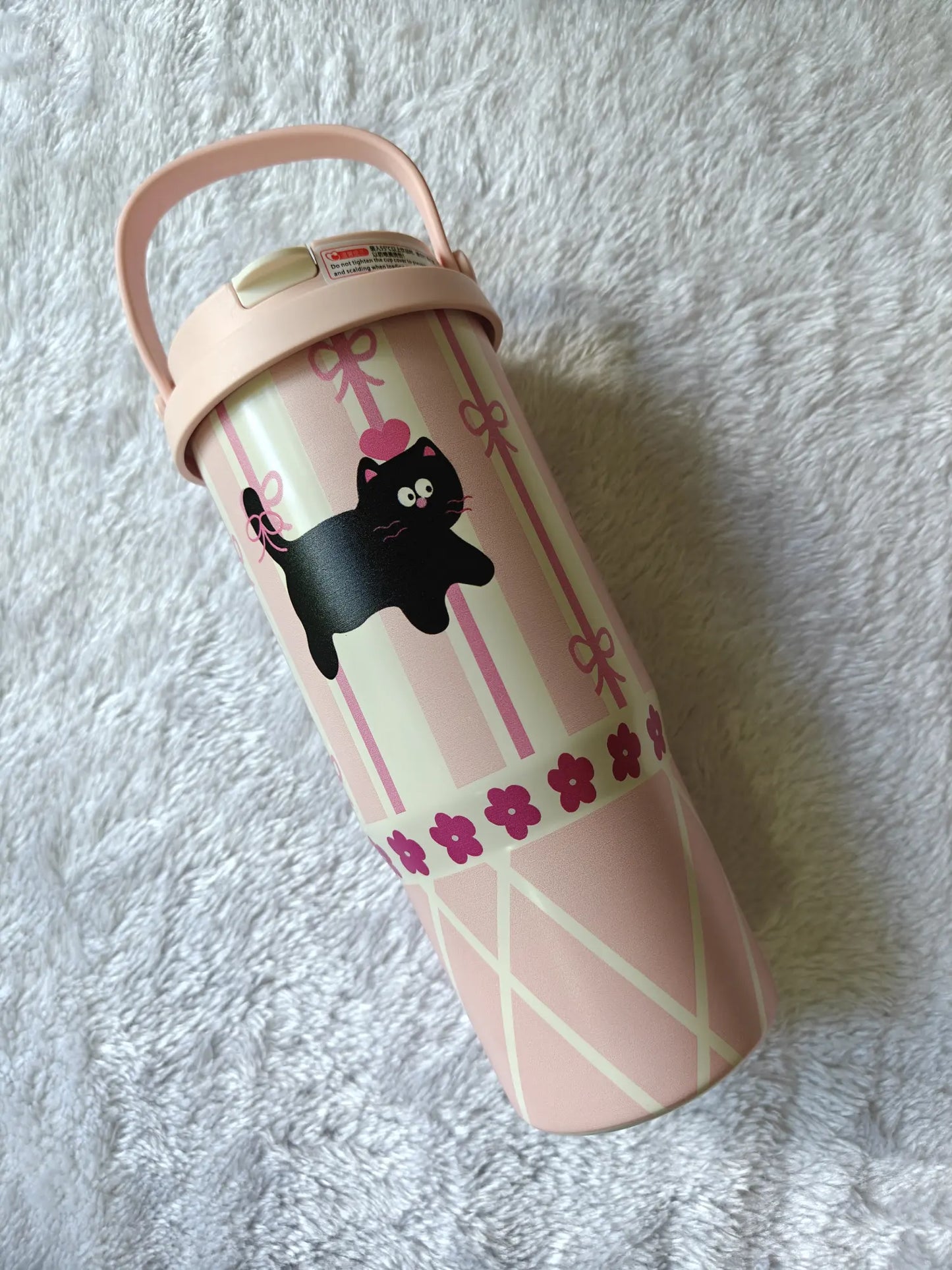 Pink tumbler with black cat design on a white textured background