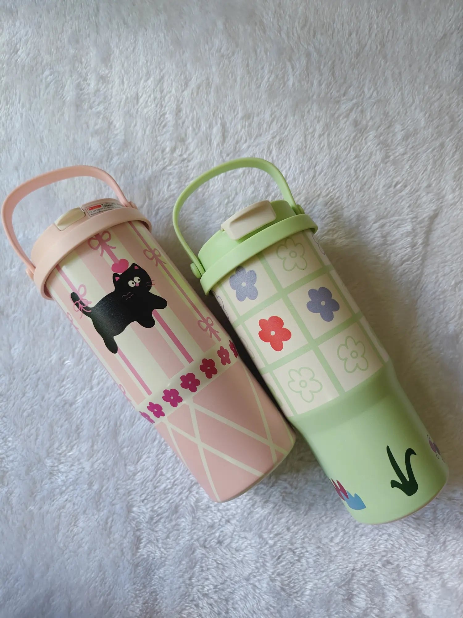 Two colorful water bottles with cartoon designs on a textured surface