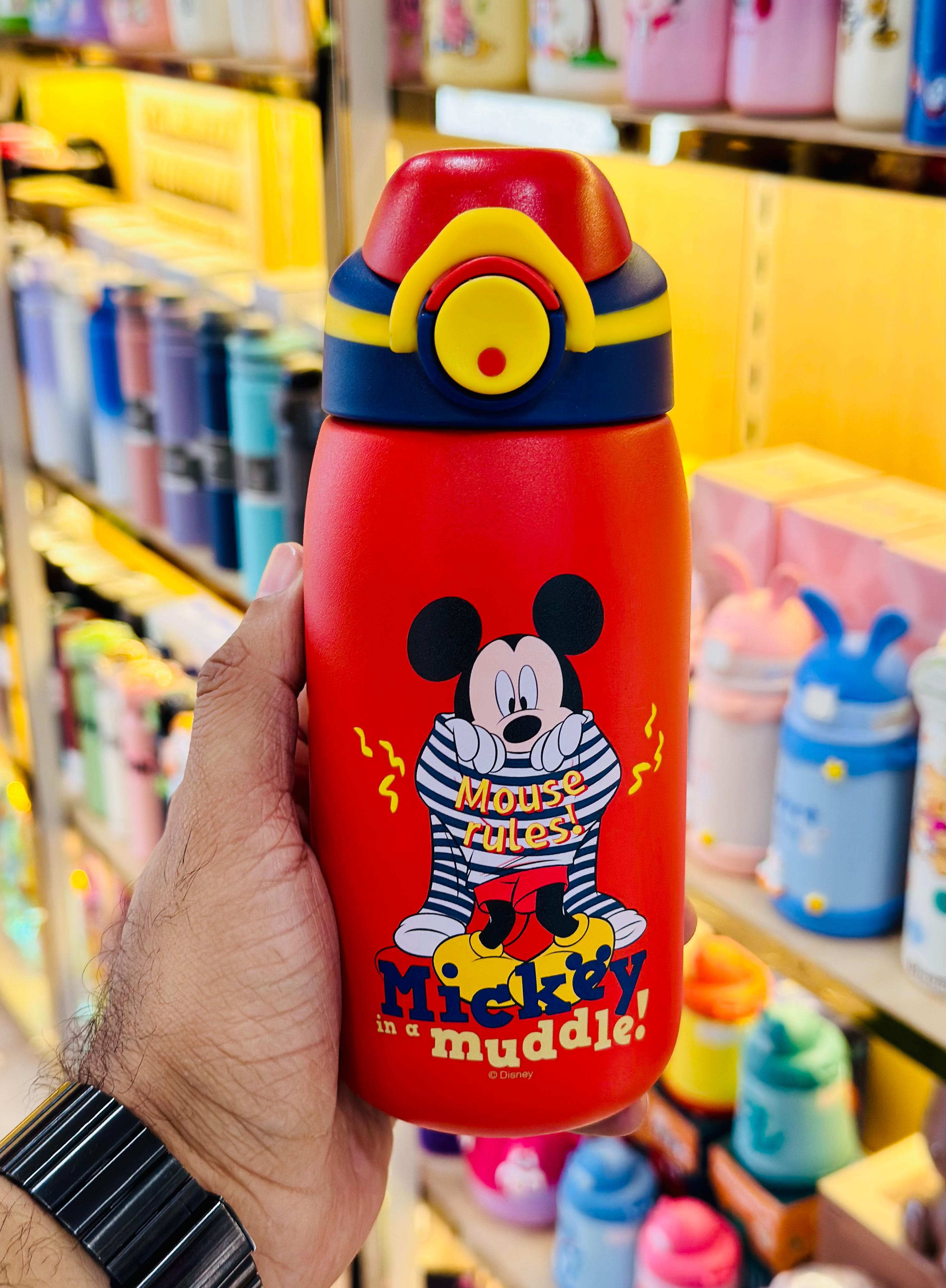 Colorful Mickey Mouse-themed water bottle held in a hand with a store shelf in the background.