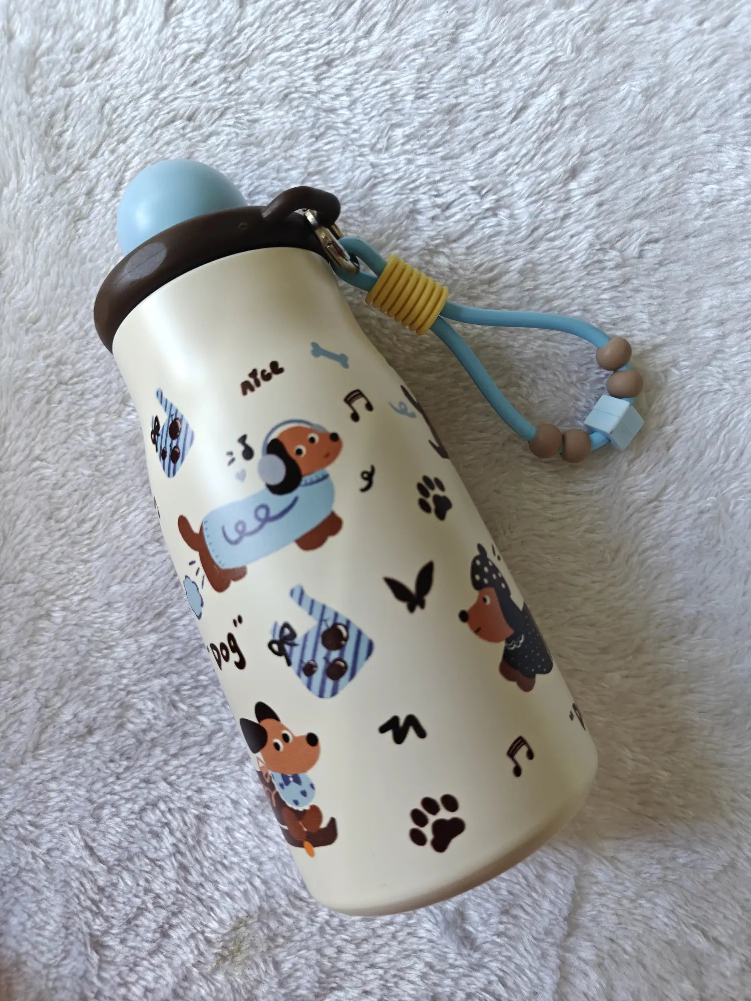 Children's water bottle with dog pattern on a textured white surface