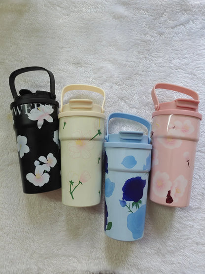 Four colorful water bottles with floral designs on a textured surface