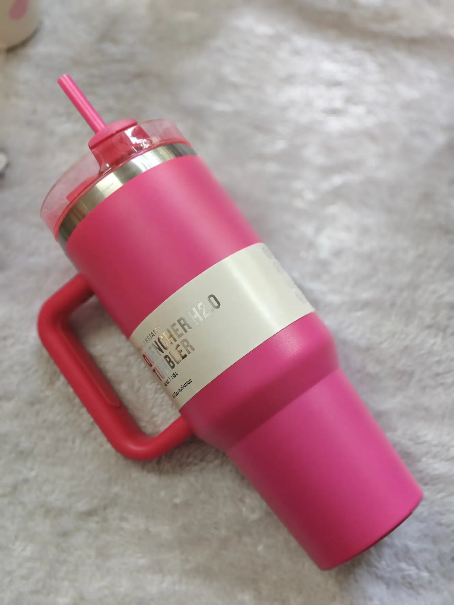 Pink water bottle with straw lid on a textured surface