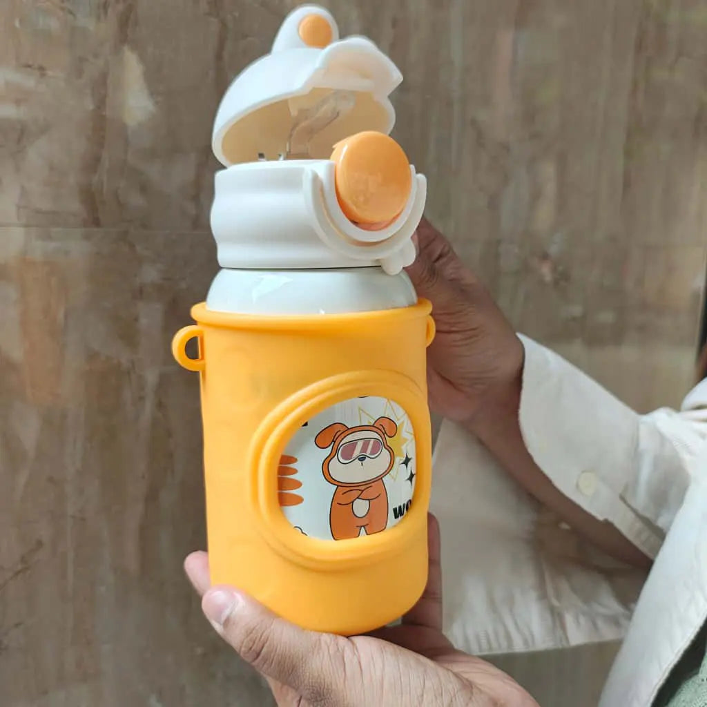 Hand holding a yellow water bottle with cartoon design against a neutral background