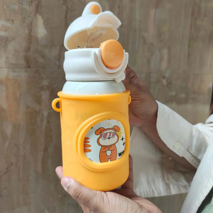 Hand holding a yellow water bottle with cartoon design against a neutral background