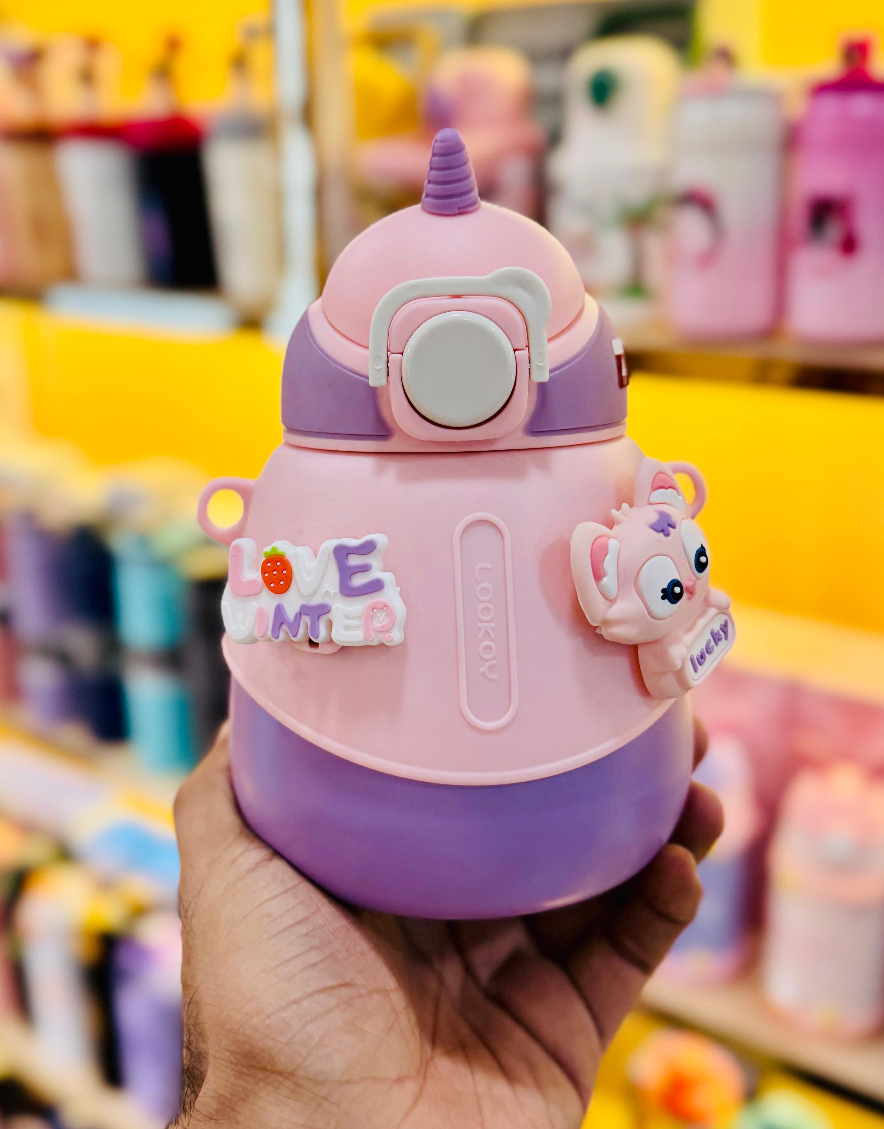 Children's tumbler with cartoon design held in a hand against a blurred store background