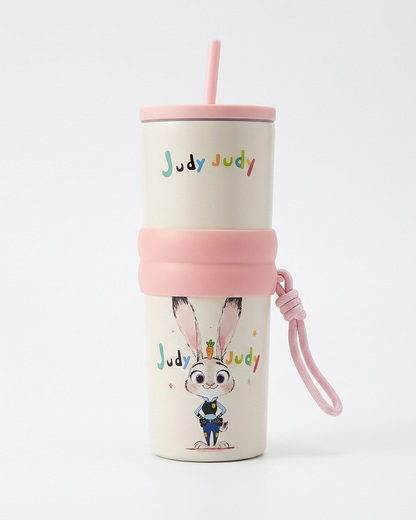 A cream-colored insulated travel tumbler with a pink lid, straw, silicone sleeve, and matching wrist strap. The cup features a cartoon illustration of Judy Judy from Zootopia and the text 'Judy Judy' printed above it.