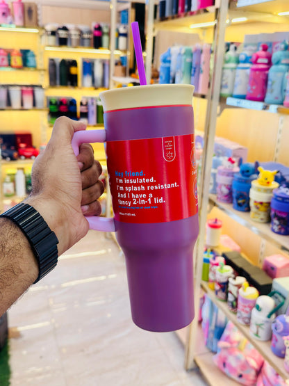 Person holding a purple and red insulated mug with text in a store setting
