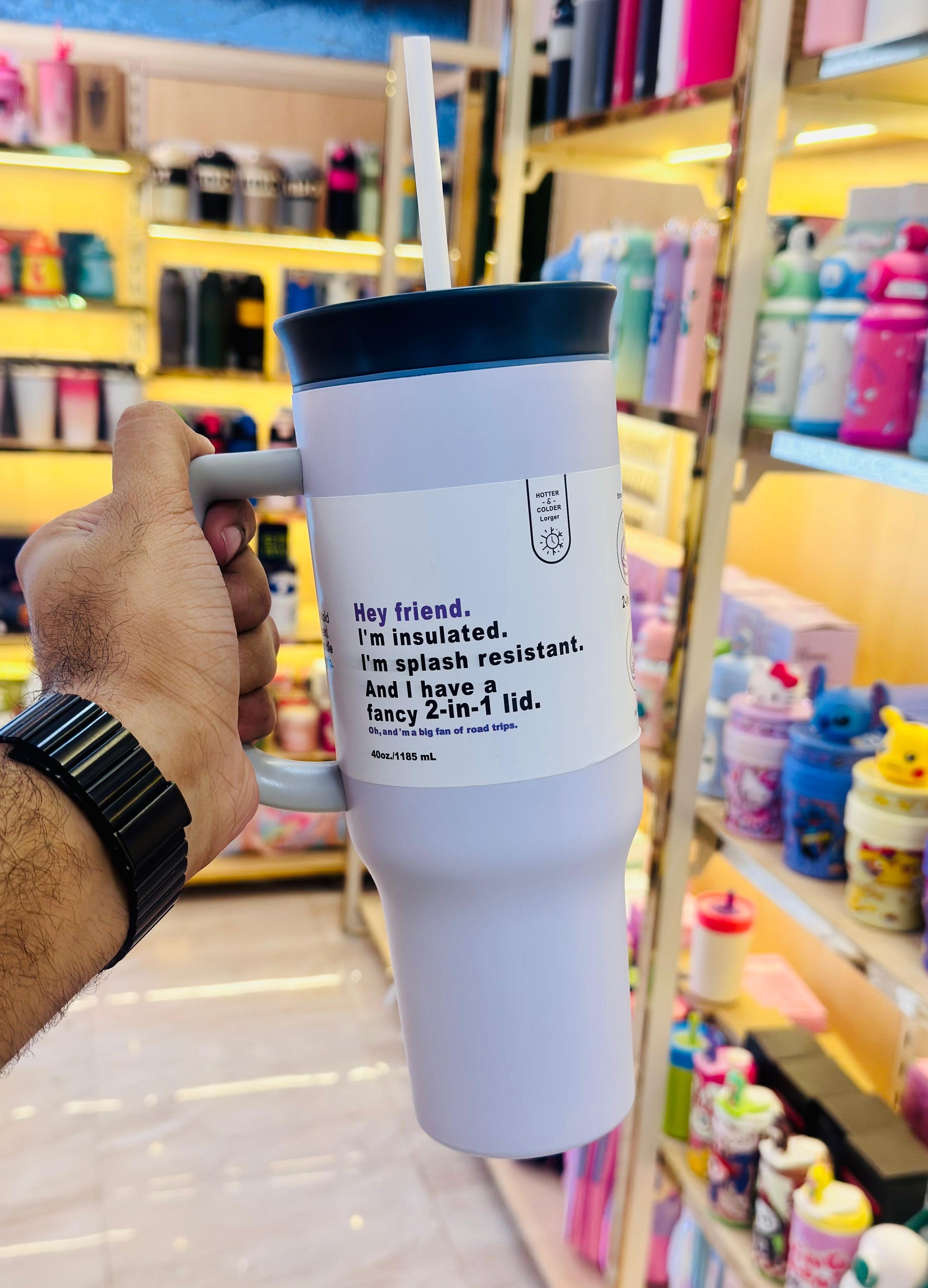 Person holding a insulated tumbler with a label in a store setting
