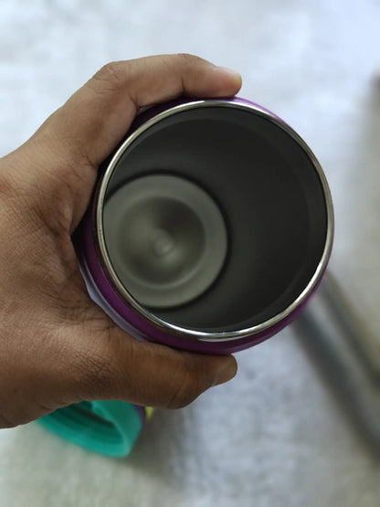 Hand holding a purple and silver thermos against a white background