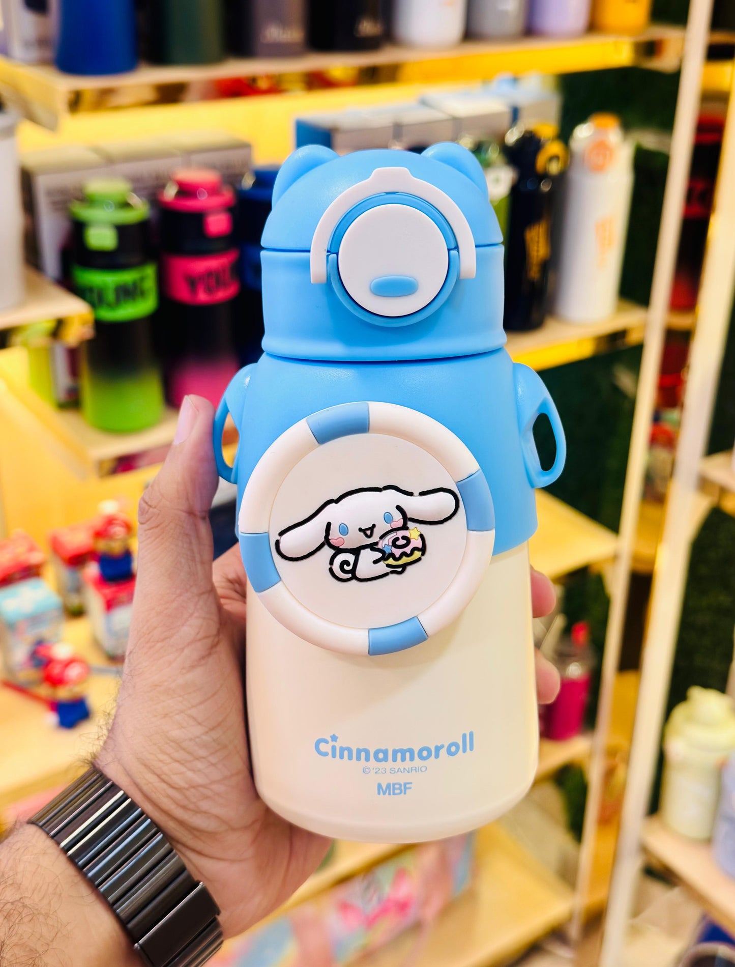 Cartoon character-themed water bottle held in a hand with a blurred store background