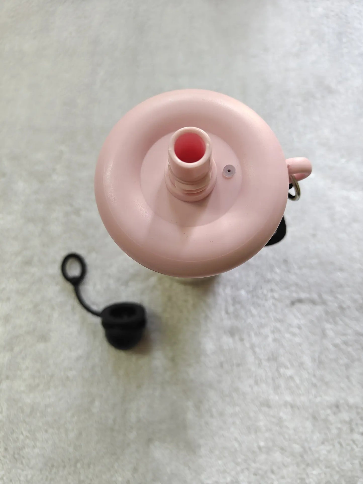 Pink bottle cap with a black cap on a light gray background