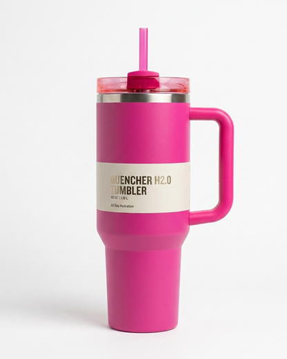 A bright pink insulated travel tumbler with a matching pink handle and straw, featuring a cream paper band label that reads 'QUENCHER H2.0 TUMBLER' on a clean white background.