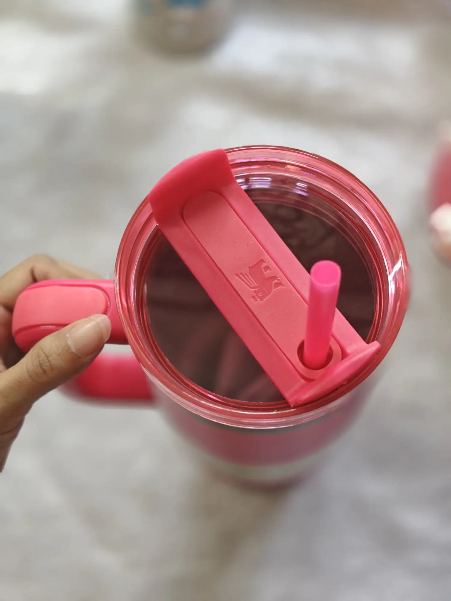 Hot pink tumbler with a pink straw on a light surface