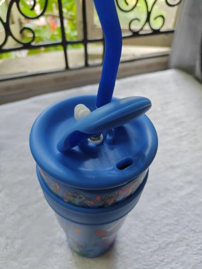 Blue sippy cup with straw lid on a textured surface