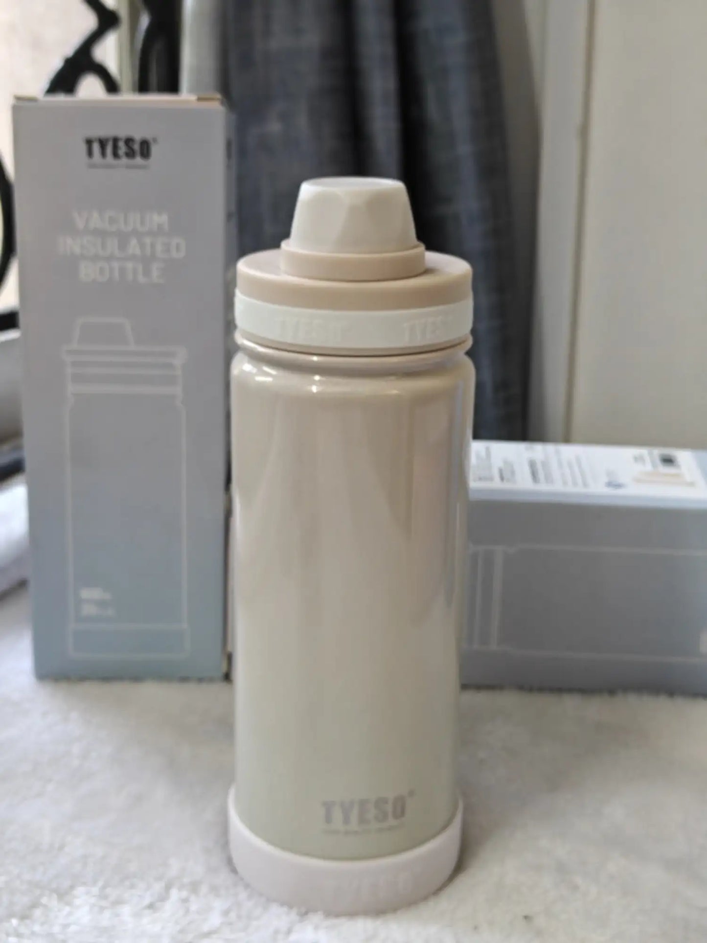 Beige vacuum insulated bottle with TYESO branding on a white surface.