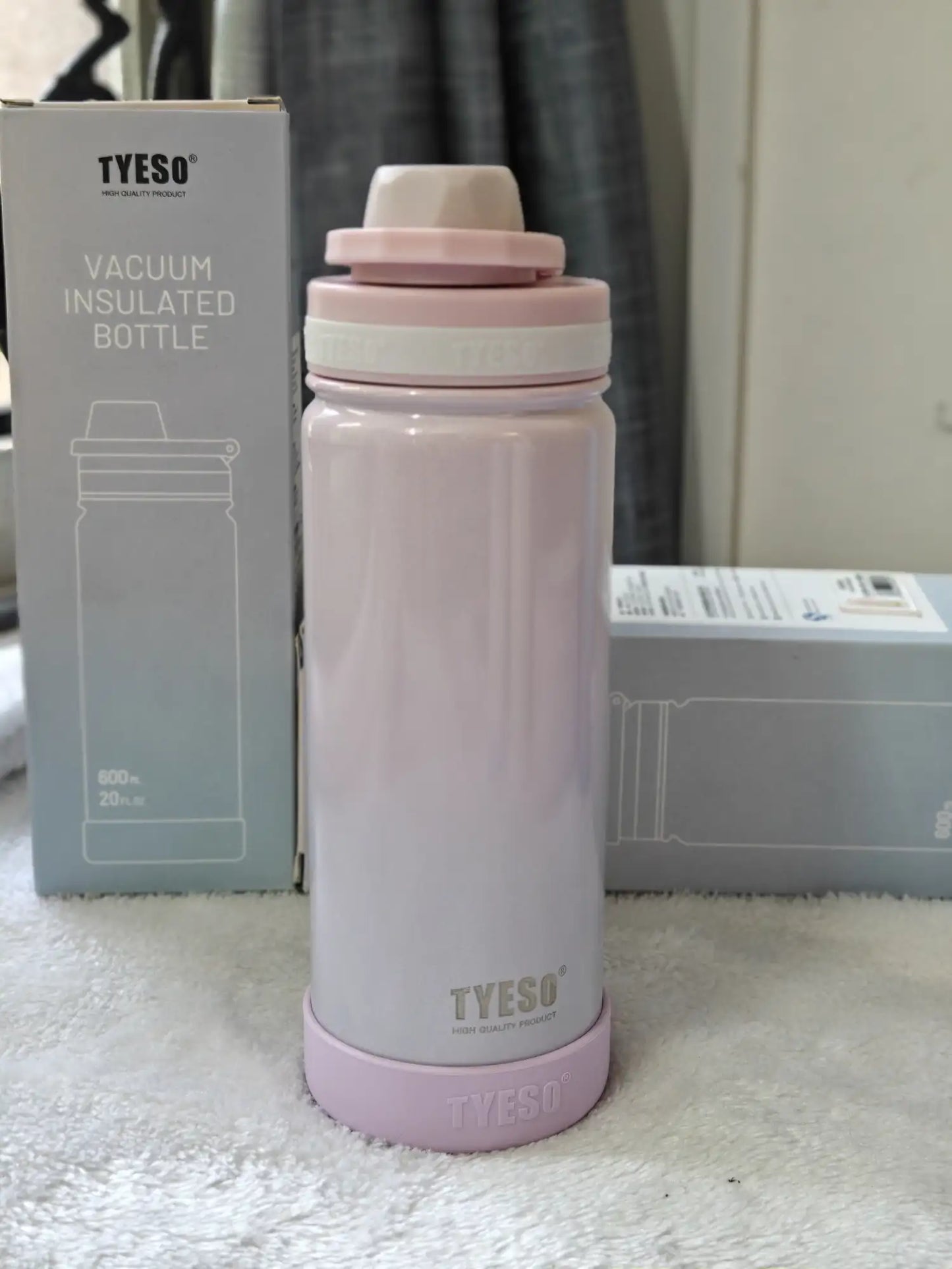 Pink vacuum insulated bottle with TYESO branding next to its packaging on a white surface.