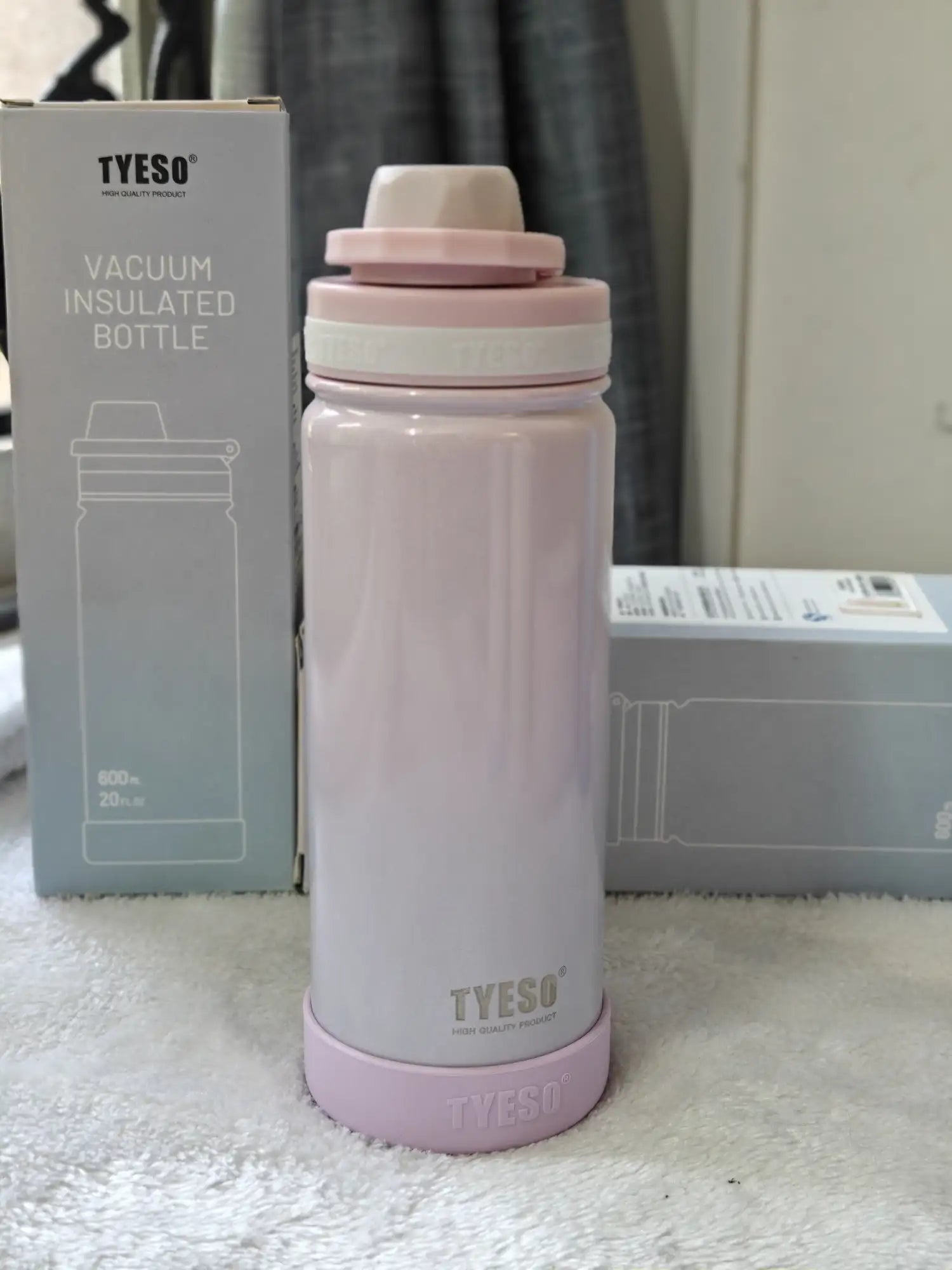Pink vacuum insulated bottle with TYESO branding next to its packaging on a white surface.