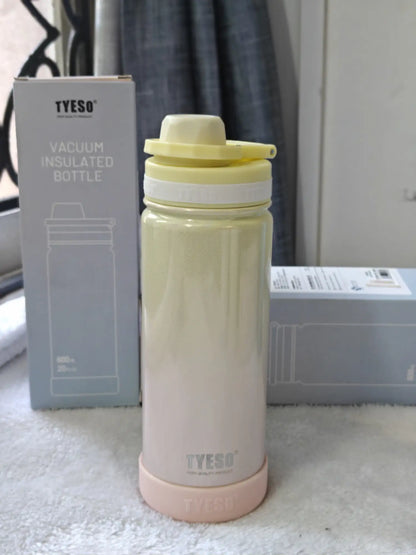 TYESO vacuum insulated bottle with pink base and yellow lid on a white surface.