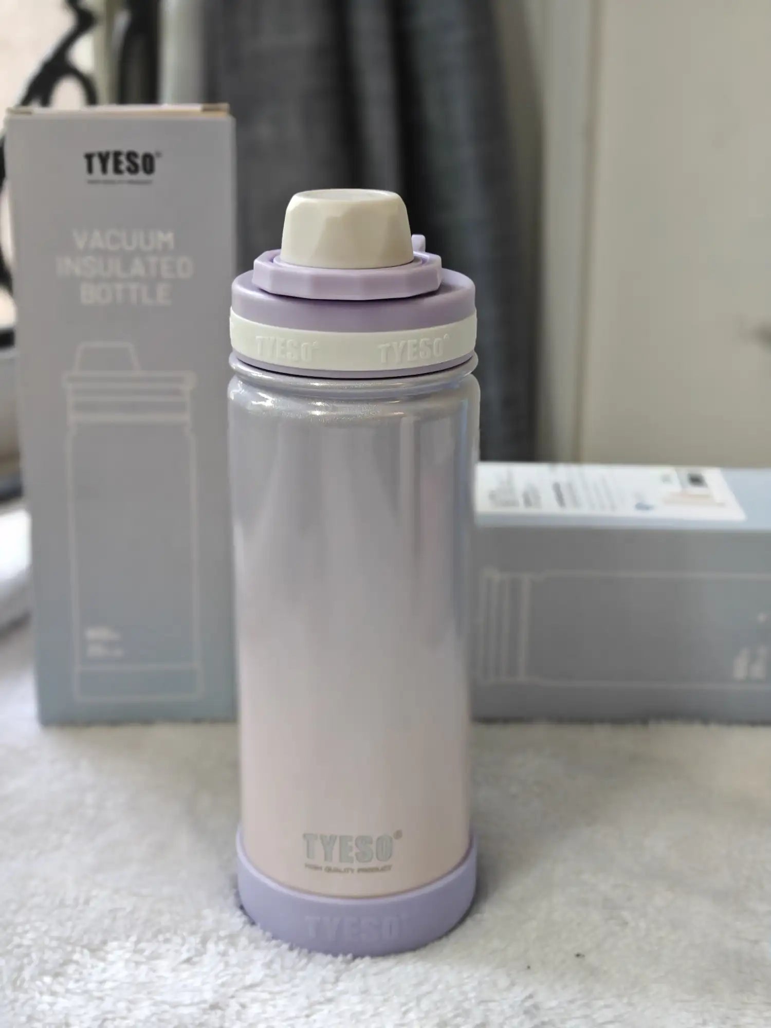 Vacuum insulated bottle with purple accents on a white surface, with TYESO packaging in the background.