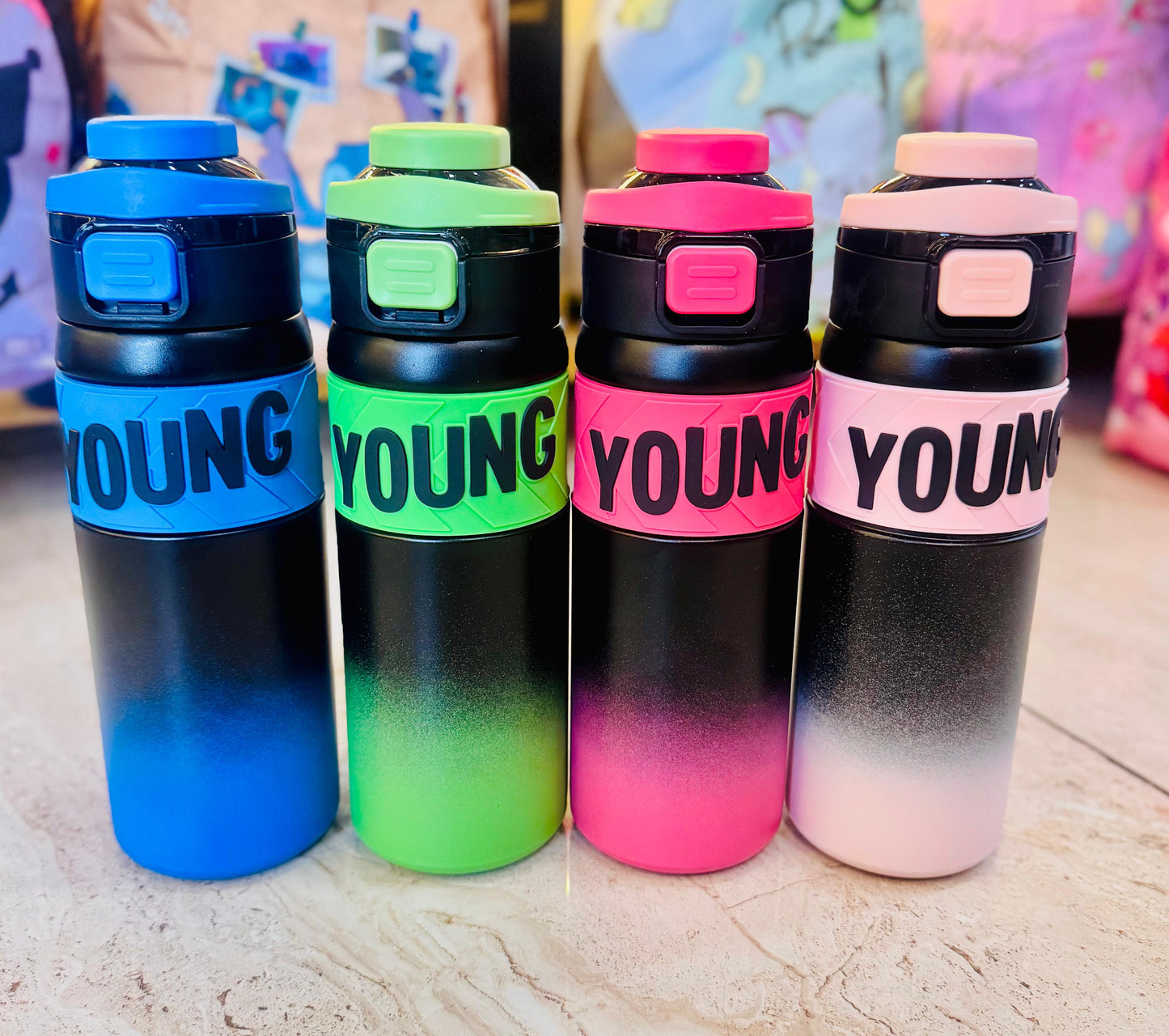 Four colorful water bottles with 'YOUNG' branding on a light surface.