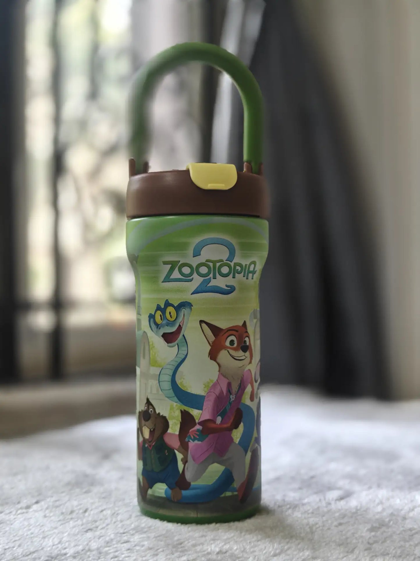 Zootopia-themed tumbler with cartoon characters on a carpeted floor.