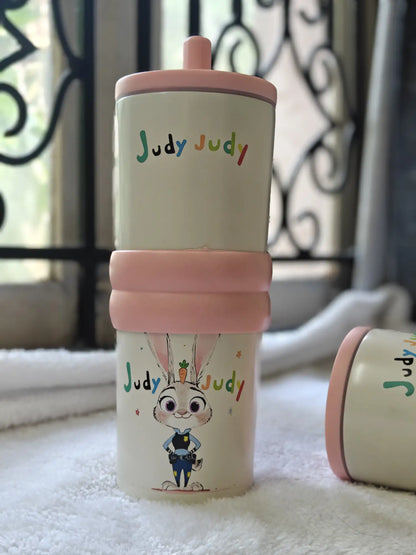 Children's tumbler with 'Judy Judy' text and cartoon character on a white surface.