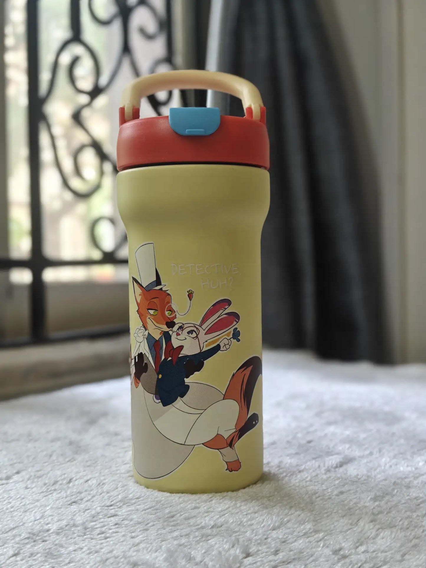 Yellow water bottle with cartoon character on a white surface