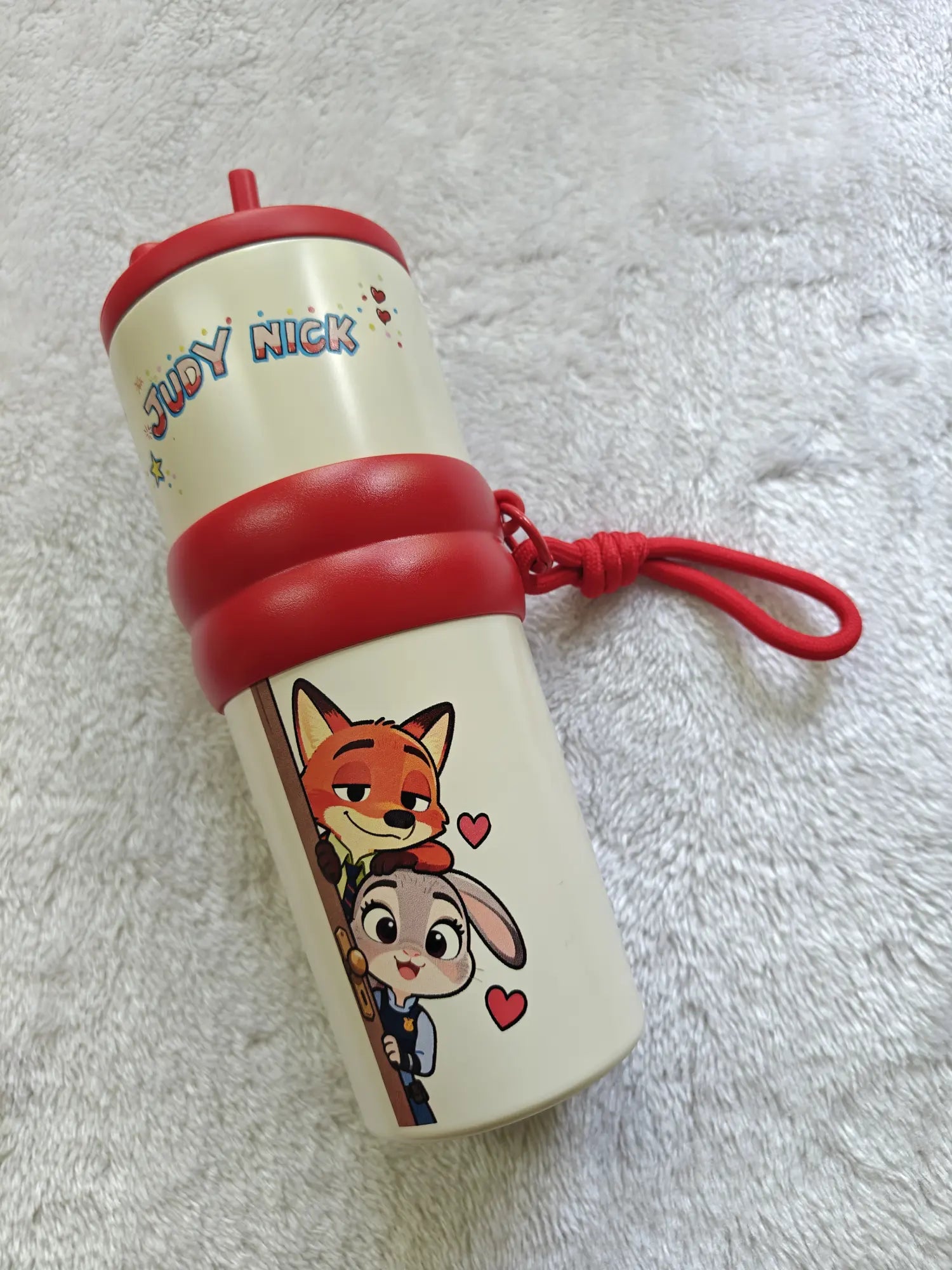 Children's tumbler with cartoon characters on a white fluffy surface